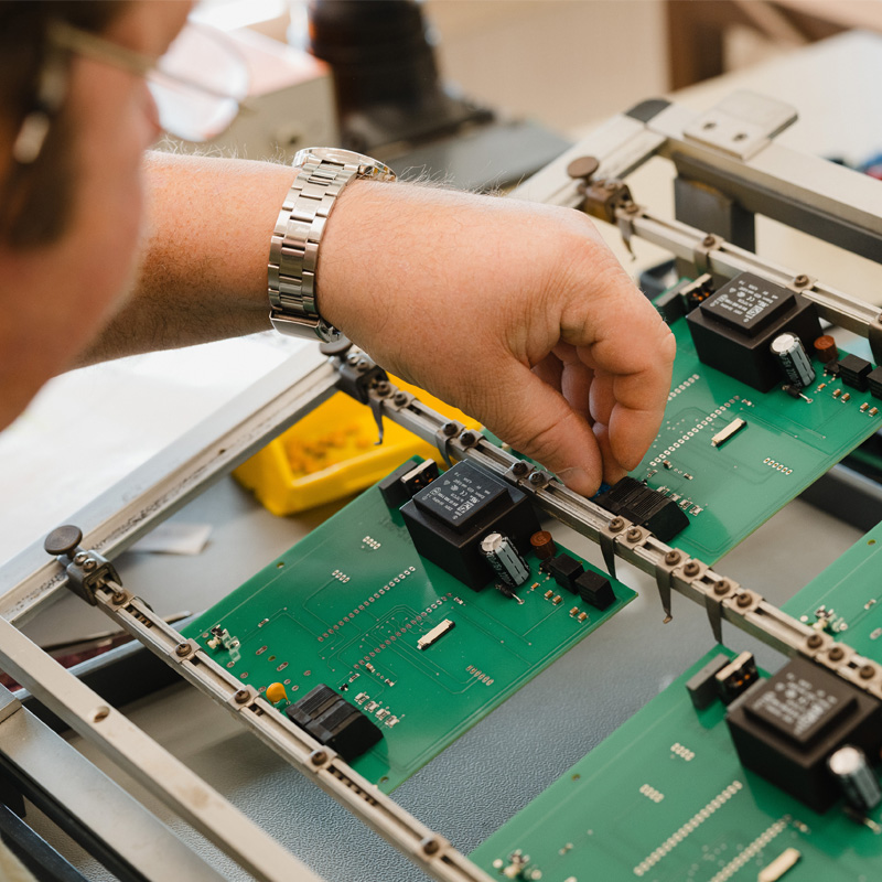 Feinmechanische Arbeit an einer Platine – Präzision in der Mess- und Regeltechnik bei Schwille Elektronik GmbH Männliche Hand arbeitet präzise und feinmechanisch an einer Platine im Bereich der Mess- und Regeltechnik bei Schwille Elektronik GmbH